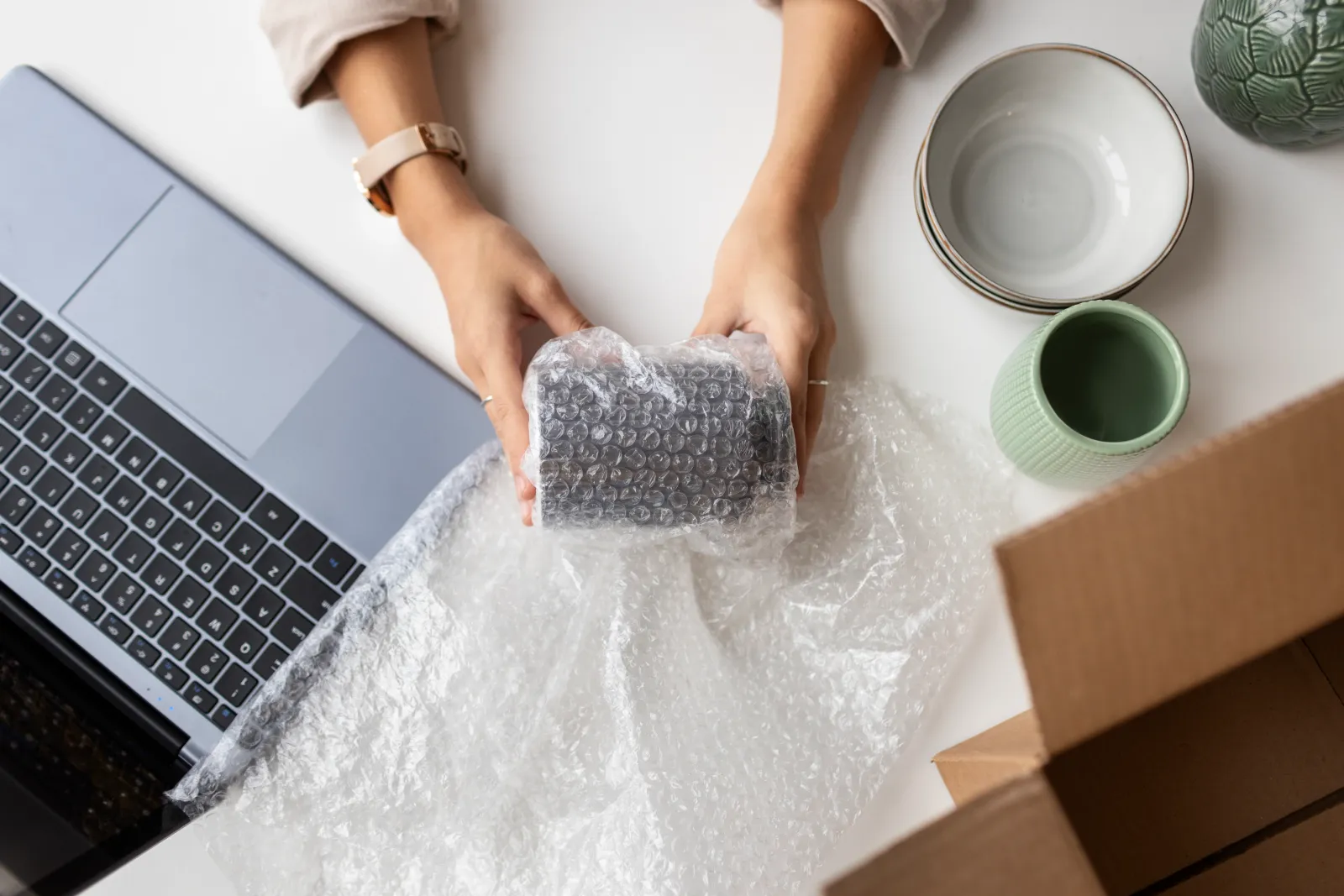Person wrapping ceramic plates in packing paper