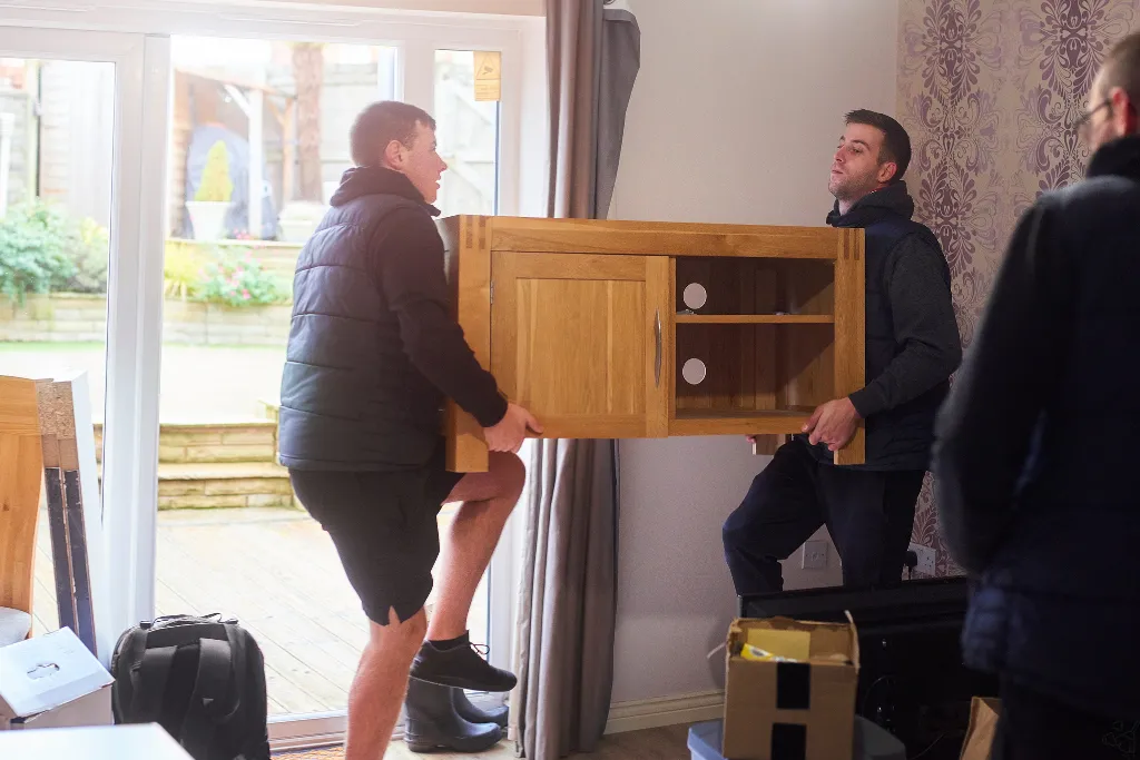 A local removals crew loading a long-wheelbase van outside a UK home